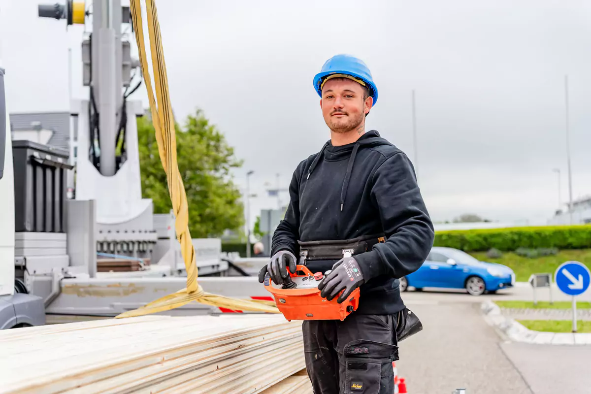 Dachdecker auf einer Baustelle mit Bedinungskonsole für einen Krahn steht auf einer Baustelle