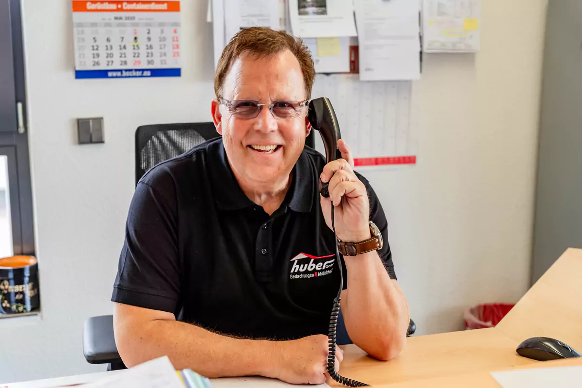 Mann mit Brille telefoniert und lächelt in die Kamera