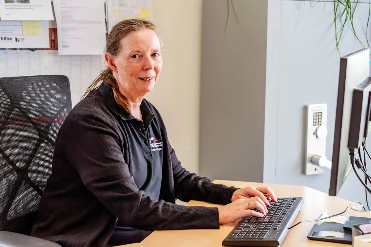Frau sitzt am Computer und tippt auf der Tastatur