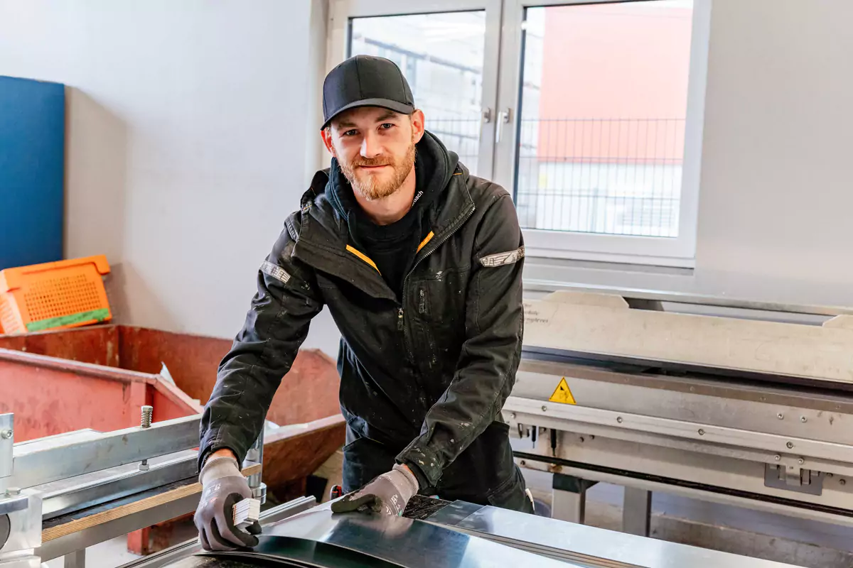 junger Handwerker fertigt Belchzuschnitte für Dächer an