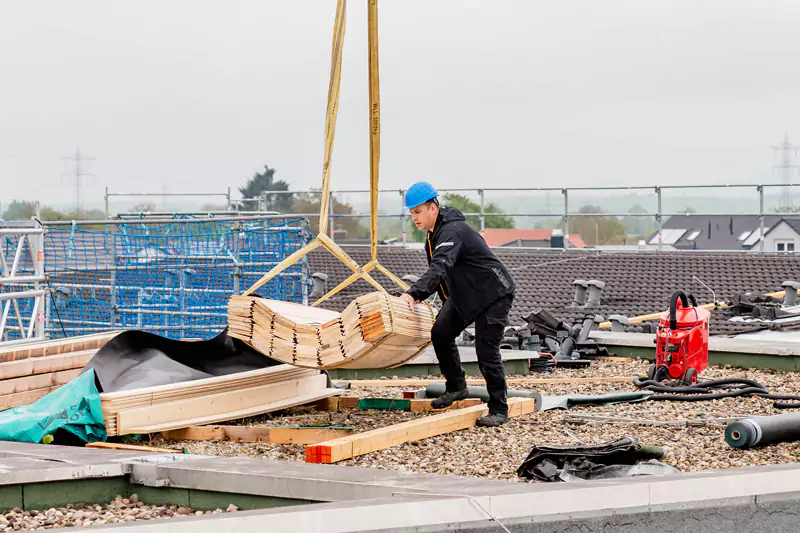 Dachdecker platziert Holzpaletten auf einem Dach