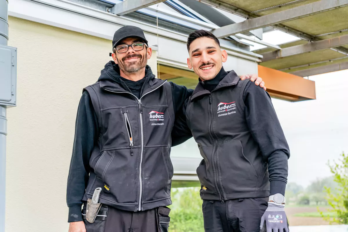 2 Handwerker haben die Arme auf den Schultern des anderen und lächeln