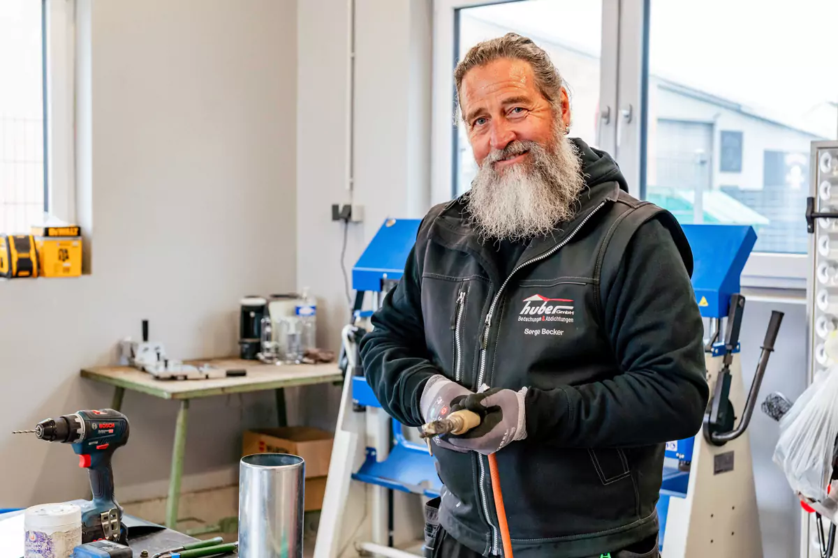 älterer Mann mit Bart hält eine Bohrmaschine